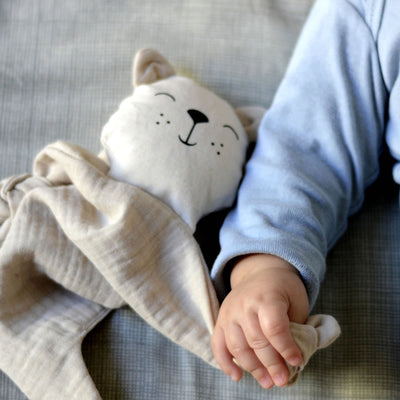 Baby hand holding aPunt Barcelona organic cotton cuddle bear