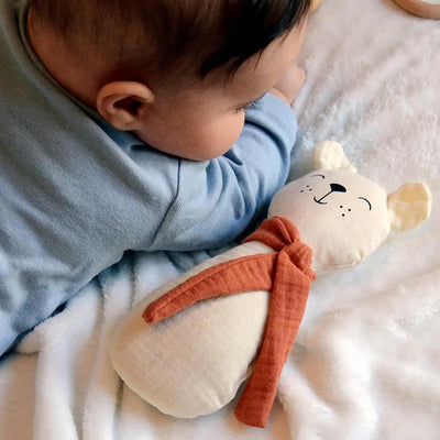 Baby lying on stomach looking at aPunt Barcelona organic cotton bear rattle