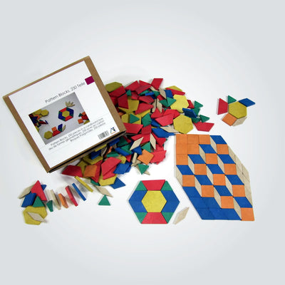 Wissner pattern blocks in pile beside cardboard packaging box and some pieces placed into patterns