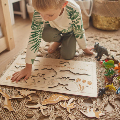 Boy doing Stuka Puka dinosaur puzzle on rug